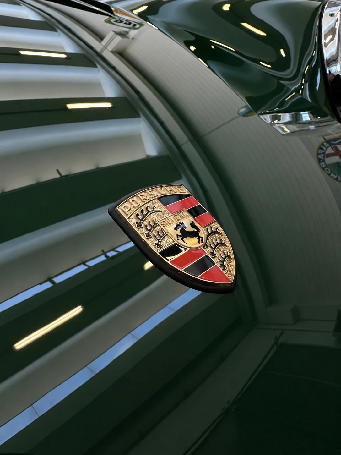 Dettaglio del cofano verde e dello stemma Porsche sulla 912 dopo la lucidatura